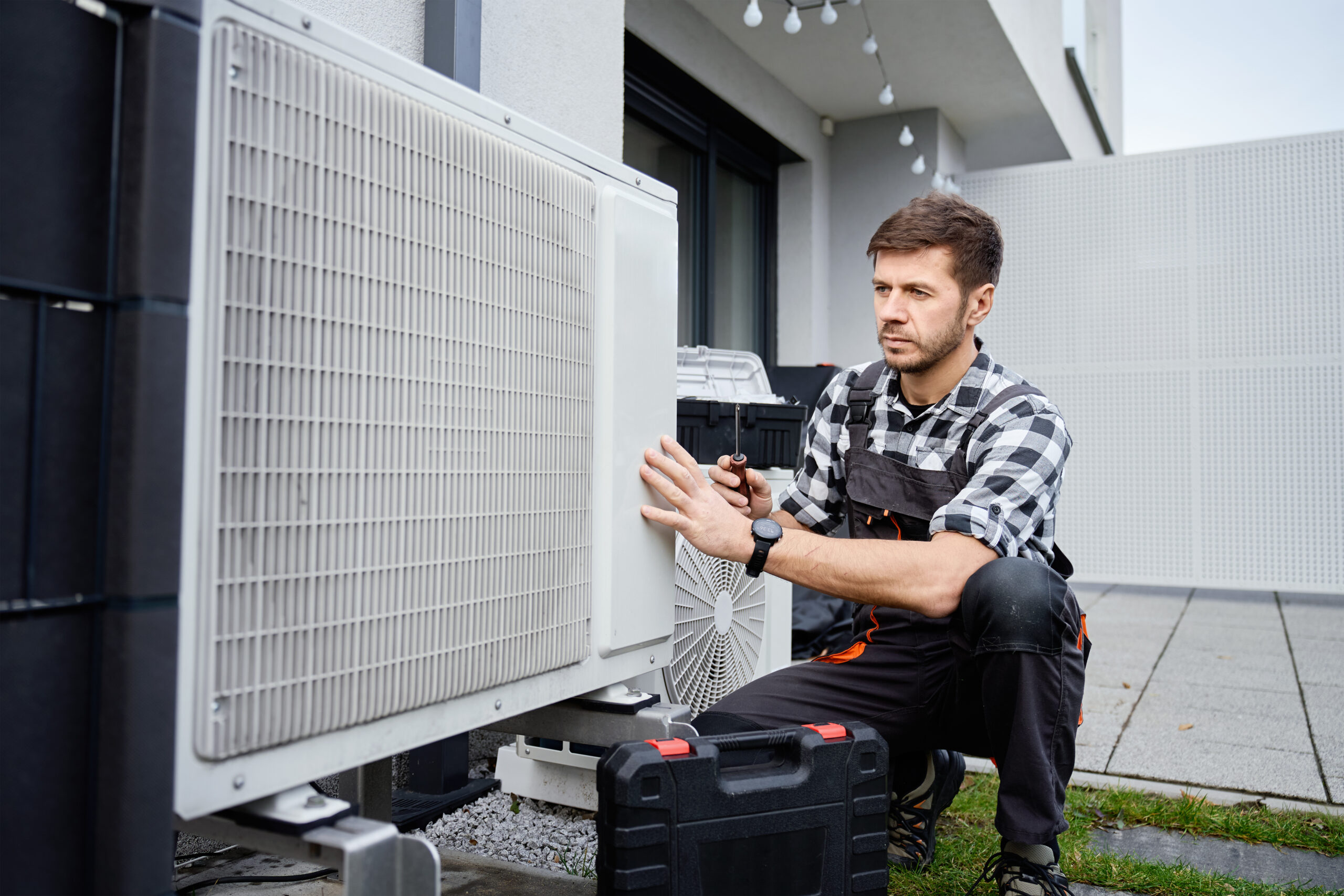 Technician servicing outdoor air source heat pump unit near house wall Techniker bei der Installation einer Ausseneinheit einer Klimaanlage in Solothurn